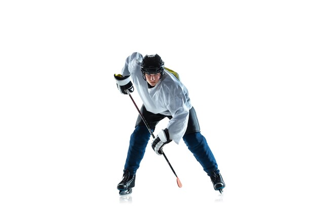 In esecuzione. Giovane giocatore di hockey maschio con il bastone sul campo da ghiaccio e sfondo bianco. Sportivo che indossa attrezzature e pratica del casco. Concetto di sport, stile di vita sano, movimento, movimento, azione.