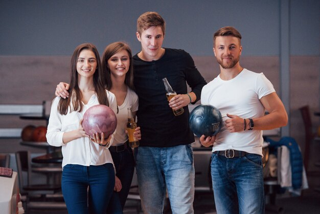 In posa per la telecamera. I giovani amici allegri si divertono al bowling durante i fine settimana