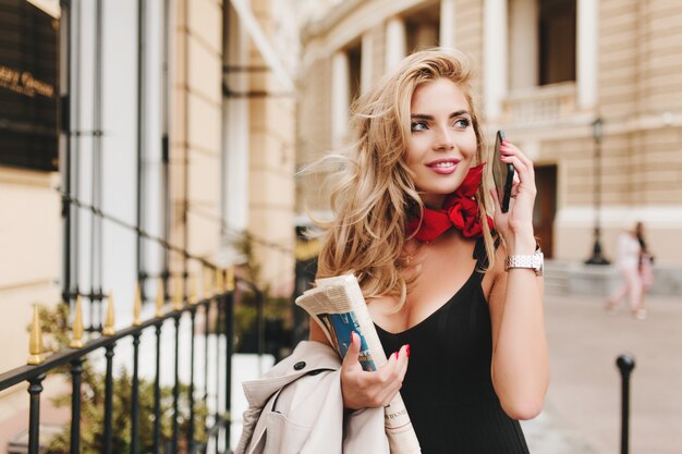 Incantevole modello femminile abbronzato che guarda lontano con un sorriso ispirato appeso fuori