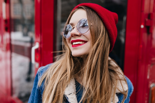 Incredibile donna bianca in giacca di jeans in posa con il telefono sul rosso