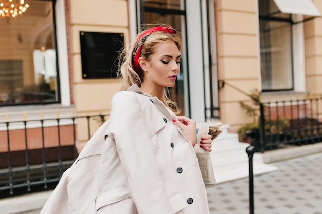 Incredibile donna con trucco alla moda e manicure che cammina per strada e guarda in basso