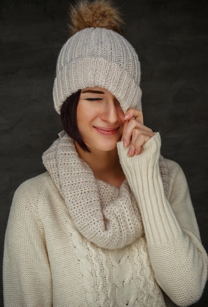 Incredibile donna sorridente in pullover bianco e cappello invernale.