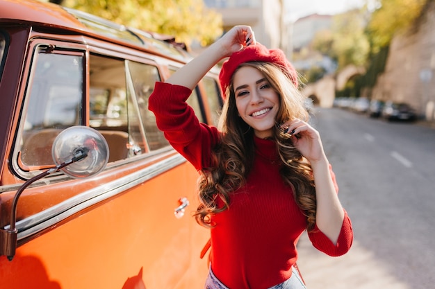 Incredibile ragazza caucasica con capelli castani ricci, trascorrere del tempo all'aperto nella soleggiata mattina di ottobre