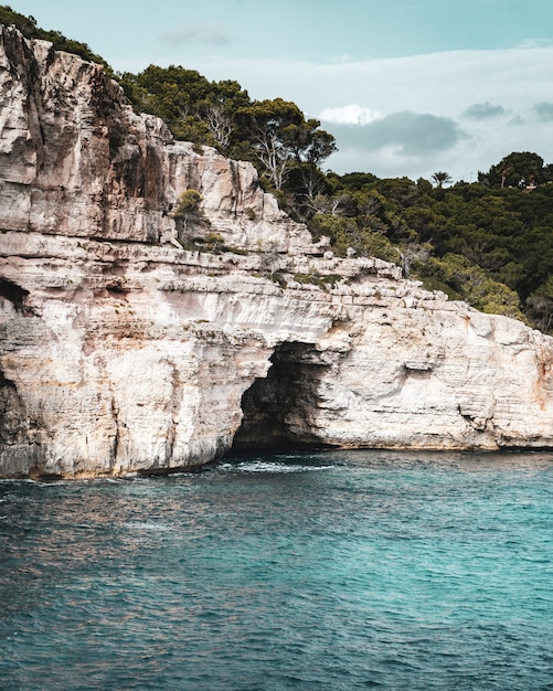 Incredibile scatto verticale di una grotta situata nell'enorme roccia e sulla riva del mare