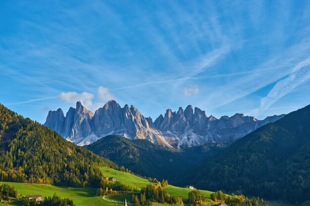 Incredibile scenario autunnale nel villaggio di Santa Maddalena con alberi colorati della chiesa e prati sotto i raggi del sole nascente Alpi Dolomitiche Italia