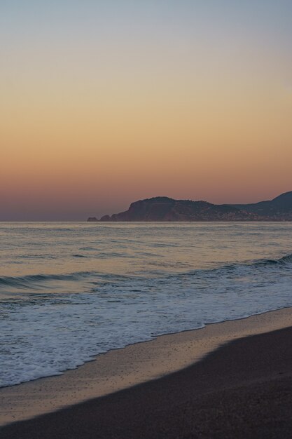 Incredibile tramonto sulla spiaggia con orizzonte infinito e figure di montagne solitarie in lontananza