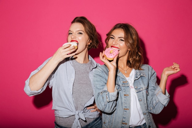 Incredibili due amiche che mangiano ciambelle