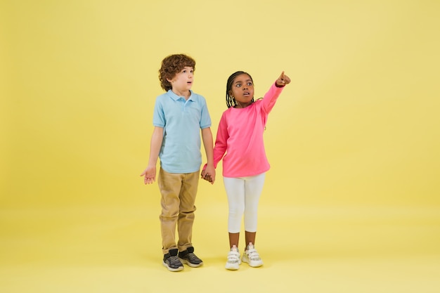 Indicare sognante. Graziosi bambini piccoli isolati su sfondo giallo.