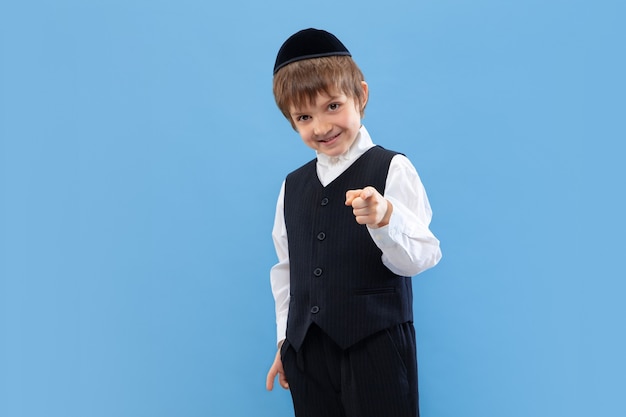 Indicazione. Ritratto di un giovane ragazzo ebreo ortodosso isolato sulla parete blu. Purim, affari, festival, vacanze, infanzia, celebrazione Pesach o Pasqua ebraica, ebraismo, concetto di religione.