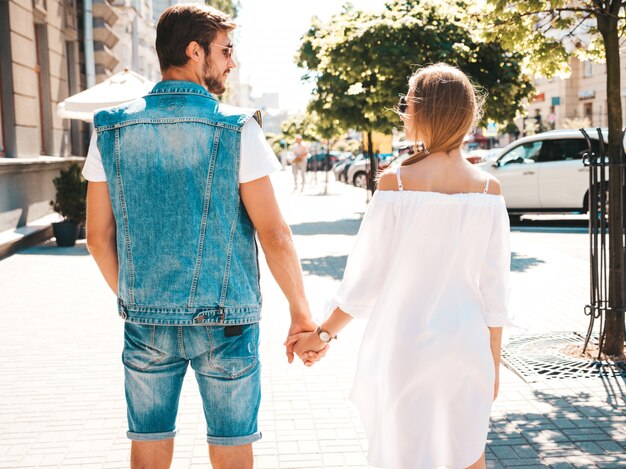 Indietro della bella ragazza e il suo bel ragazzo tenendosi per mano