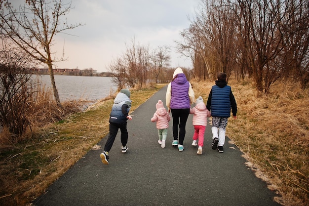 Indietro della madre che cammina con i bambini sul sentiero in riva al lago