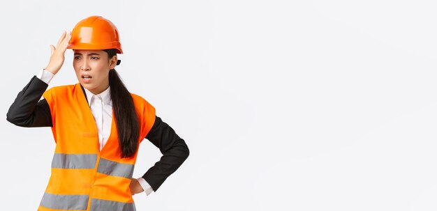 Infastidito e deluso ingegnere capo asiatico femminile che rimprovera i lavoratori edili che fanno stupido errore