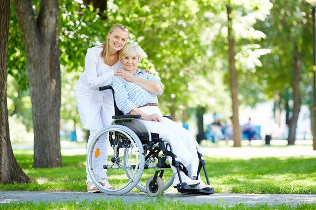 Infermiera abbracciando donna anziana in sedia a rotelle
