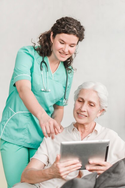 Infermiera che indica allo schermo che mostra qualcosa al suo paziente sulla compressa digitale