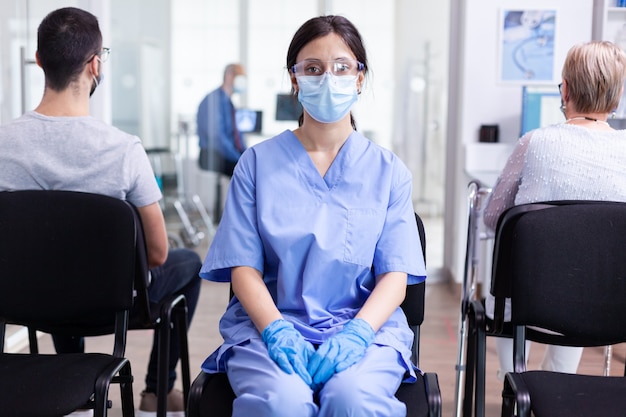 Infermiera con maschera facciale contro il coronavirus nell'area di attesa dell'ospedale