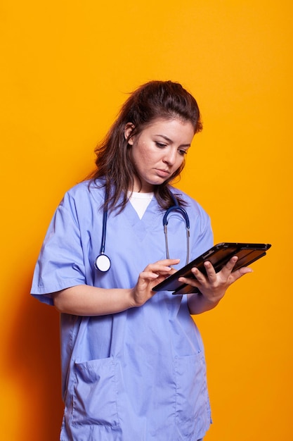 Infermiera donna che lavora con tablet digitale mentre indossa l'uniforme