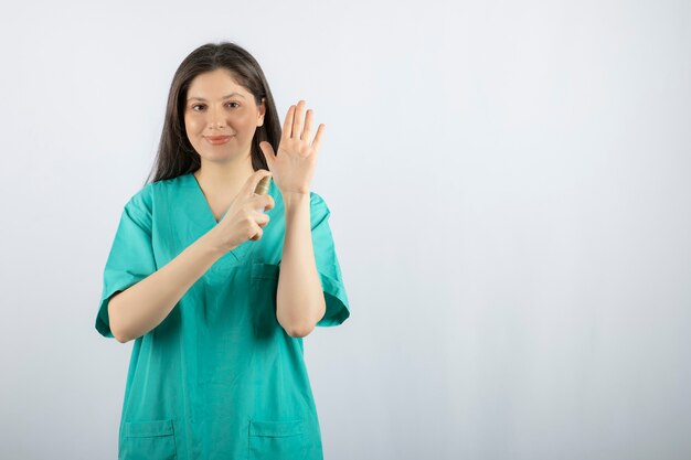 Infermiera femminile sorridente che spruzza la sua mano su bianco.