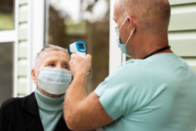 Infermiera maschio che controlla la temperatura della donna anziana