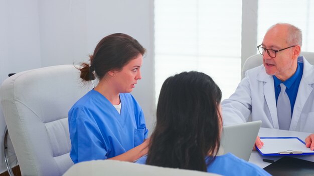 Infermieri medici che fanno lavoro di squadra indossando l'uniforme blu durante la conferenza medica accademica. Terapista clinico con colleghi che parlano di malattia, esperto, specialista, comunicazione.