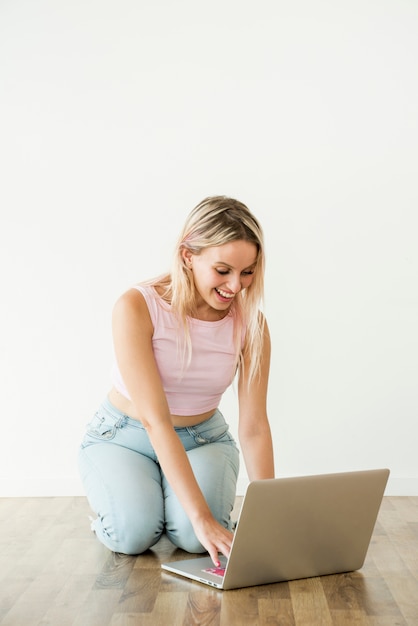 Influencer bionda usando il portatile sul pavimento