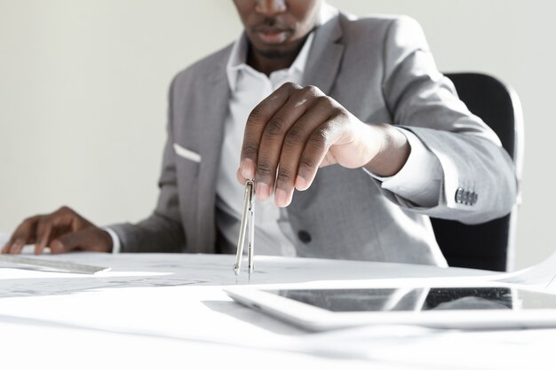 Ingegnere africano utilizzando lo strumento di disegno tecnico per il calcolo delle misurazioni