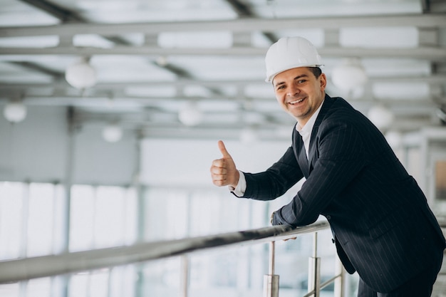 Ingegnere bello dell'uomo di affari in casco in una costruzione