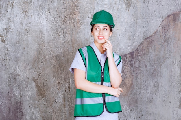 Ingegnere donna in uniforme verde e casco sembra confuso e premuroso.