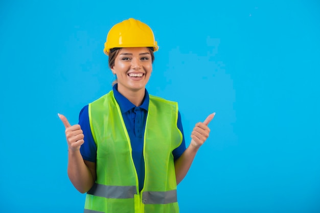 Ingegnere femminile in casco giallo e attrezzi che fanno i pollici in su.