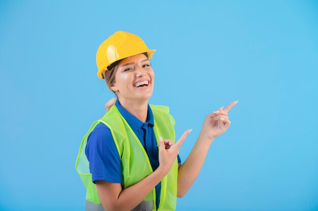 Ingegnere femminile in casco giallo e attrezzi che presentano qualcosa.