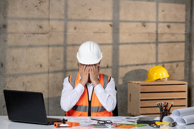 Ingegnere giovane bel ragazzo intelligente lavoratore civile in casco e giubbotto stanco e assonnato