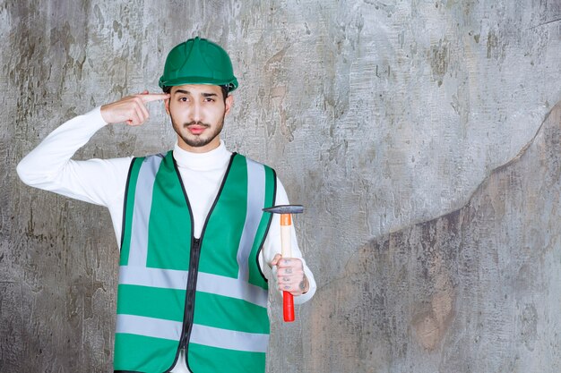 Ingegnere in uniforme gialla e casco che tiene un'ascia con manico in legno per la riparazione e sembra premuroso