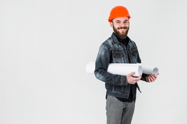 Ingegnere maschio sorridente che tiene modello acciambellato contro fondo bianco