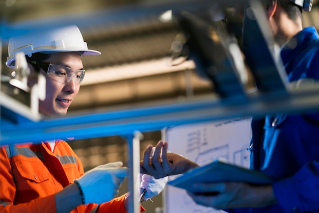 Ingegnere professionista asiatico maschio che ha una discussione in piedi accanto alla macchina in fabbrica due colleghi asiatici brainstorming che spiegano e risolve il processo curcuit scheda madre della macchina