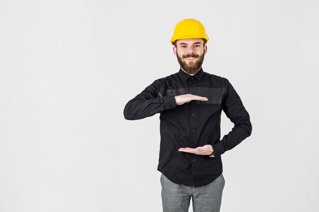 Ingegnere sorridente che indossa gesturing giallo dell&#39;elmetto protettivo