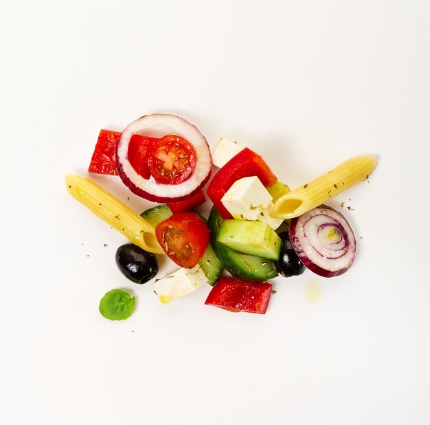Ingredienti appetitosi colorati gustosi per insalata di verdure greca con penne di pasta su sfondo luminoso. Vista dall&#39;alto.