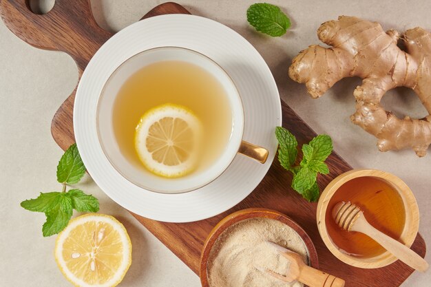 Ingredienti del tè allo zenzero, tè salutare, confortante e riscaldante con una ricetta semplice. Tè allo zenzero e ingredienti - limone, miele Vista dall'alto. Lay piatto. appena dal giardino biologico di crescita domestica. Concetto di cibo.