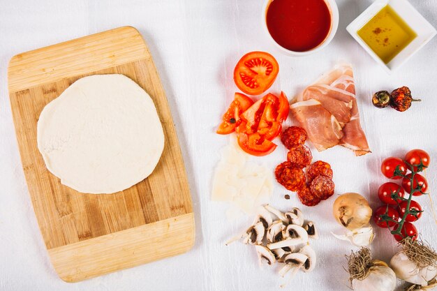 Ingredienti della pizza assortiti vicino all&#39;impasto