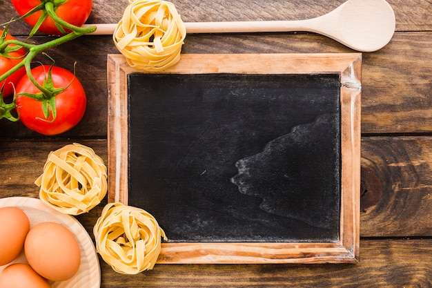 Ingredienti e cucchiaio della pasta vicino alla lavagna