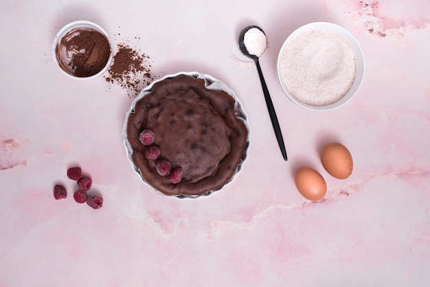 Ingredienti per torta al cioccolato con condimenti di lamponi su sfondo rosa