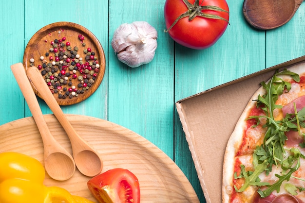 Ingredienti sani su superficie strutturata in legno con verdure e deliziosa pizza