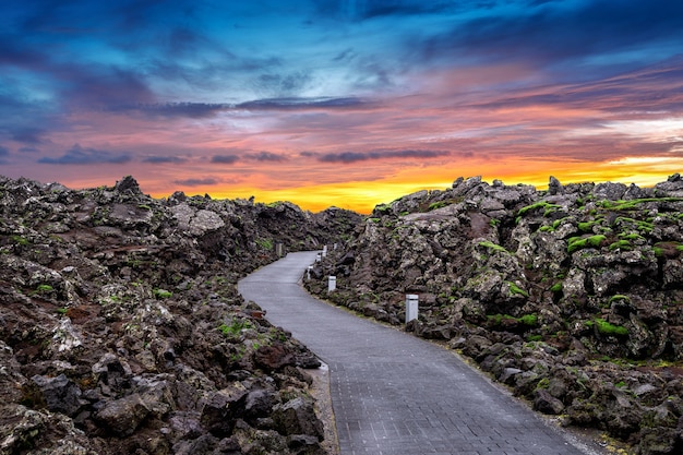 Ingresso alla laguna blu con rocce laviche e muschio verde al tramonto in Islanda.