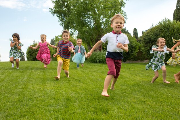 Inizio divertente. Concetto di moda per bambini. Il gruppo di ragazzi e ragazze adolescenti che corrono al parco.