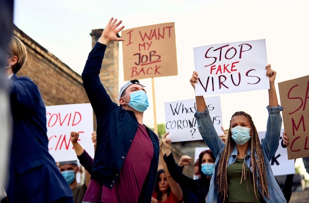 Inquadratura dal basso dei manifestanti con cartelli e cartelli che si radunano contro le misure del governo durante la pandemia COVID19