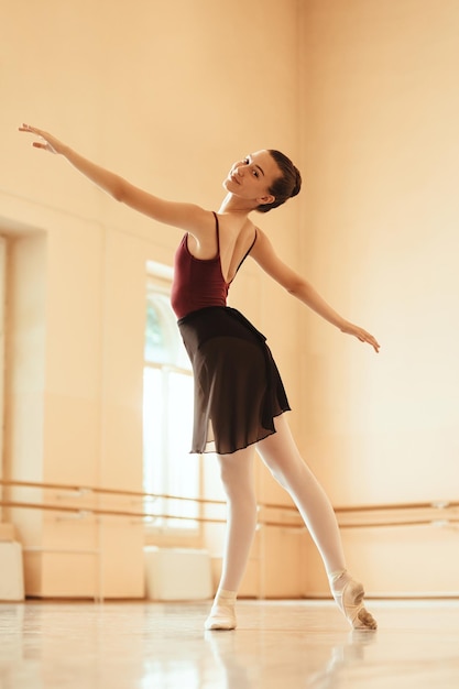 Inquadratura dal basso della ballerina sorridente che prova allo studio di danza mentre guarda la fotocamera