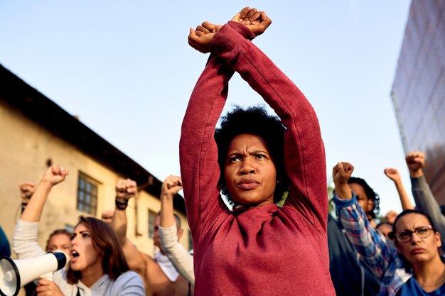 Inquadratura dal basso della donna afroamericana con gesto di incrocio delle braccia che partecipa a una protesta per i diritti umani