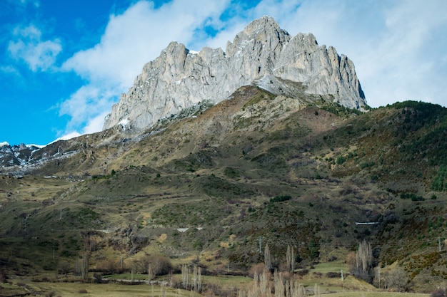 Inquadratura dal basso di un'alta rupe rocciosa in cima a una montagna sotto un cielo nuvoloso