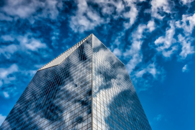 Inquadratura dal basso di un edificio di vetro alto sotto un cielo nuvoloso blu