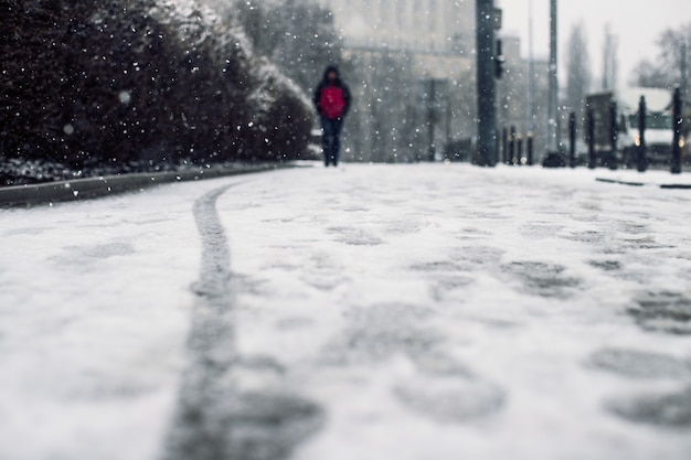 Inquadratura dal basso di una persona che cammina sul marciapiede innevato sotto la neve