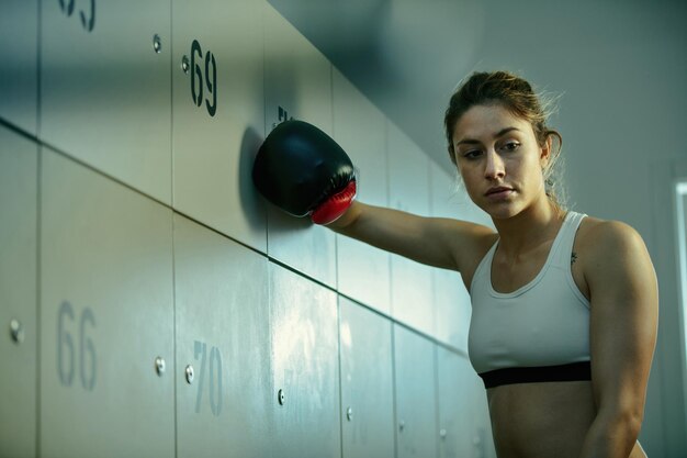 Inquadratura dal basso di una sportiva premurosa con guanti da boxe che cerca di motivarsi prima dell'allenamento sportivo