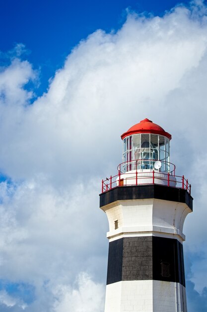 Inquadratura dal basso verticale di un faro sotto la bella nuvola nel cielo